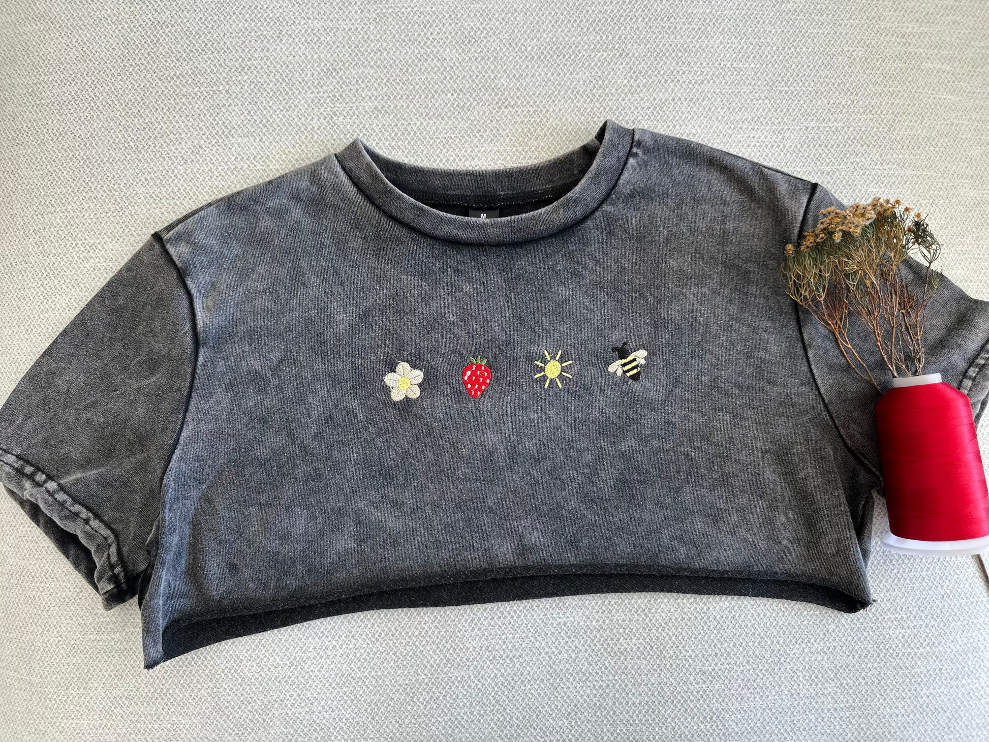 Dark gray sleeveless top with embroidered designs on a textured surface