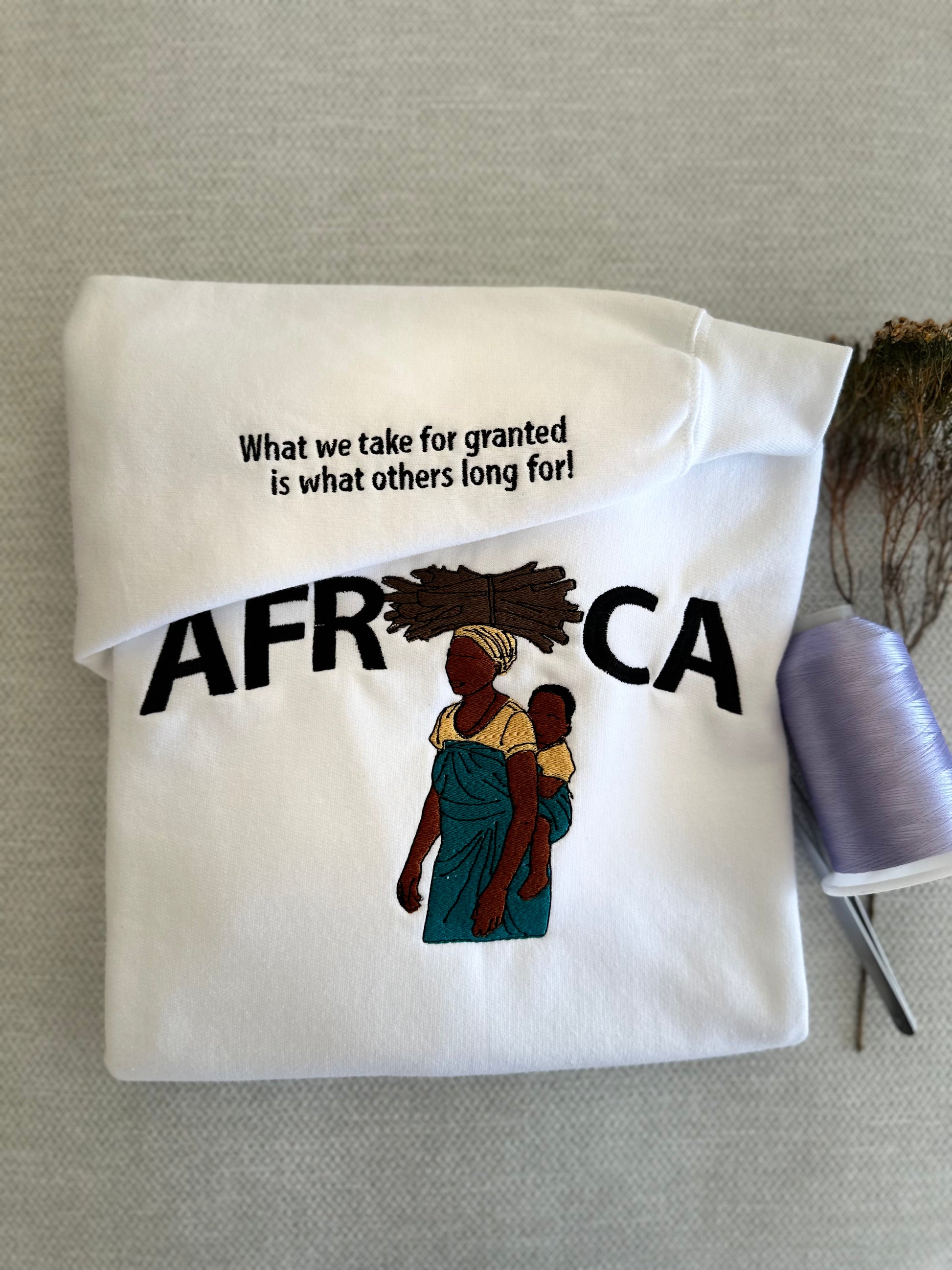 Folded white tote bag with 'AFRICA' text and graphic on a gray surface. Work logo embroidery Brisbane