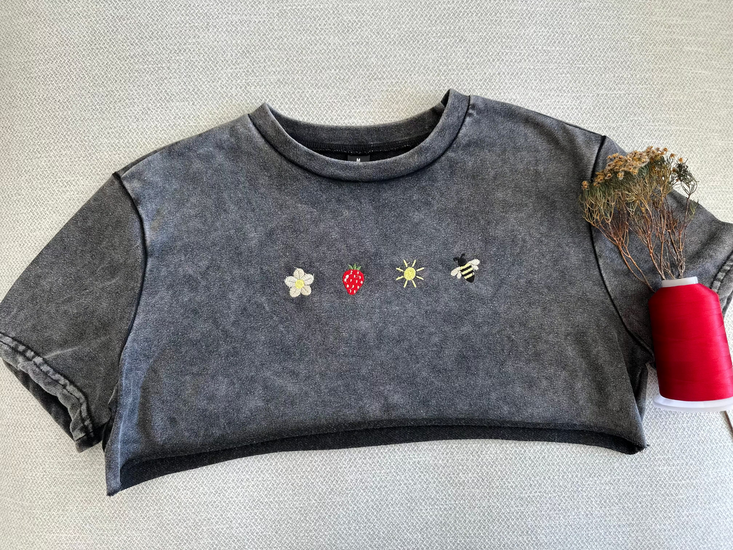 Dark gray sleeveless top with embroidered designs on a textured surface