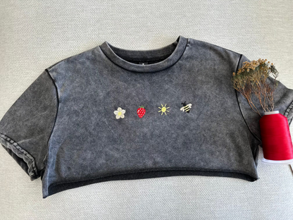 Dark gray sleeveless top with embroidered designs on a textured surface