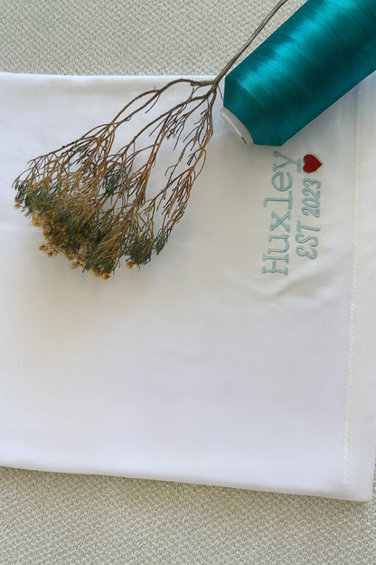 White fabric with 'Fluxley' embroidery and a teal spool of thread. handcrafted embroidered apparel
cozy embroidered crewnecks
unique embroidered accessories
bookish embroidery designs
pet-themed embroidered tees
made-to-order embroidered gifts