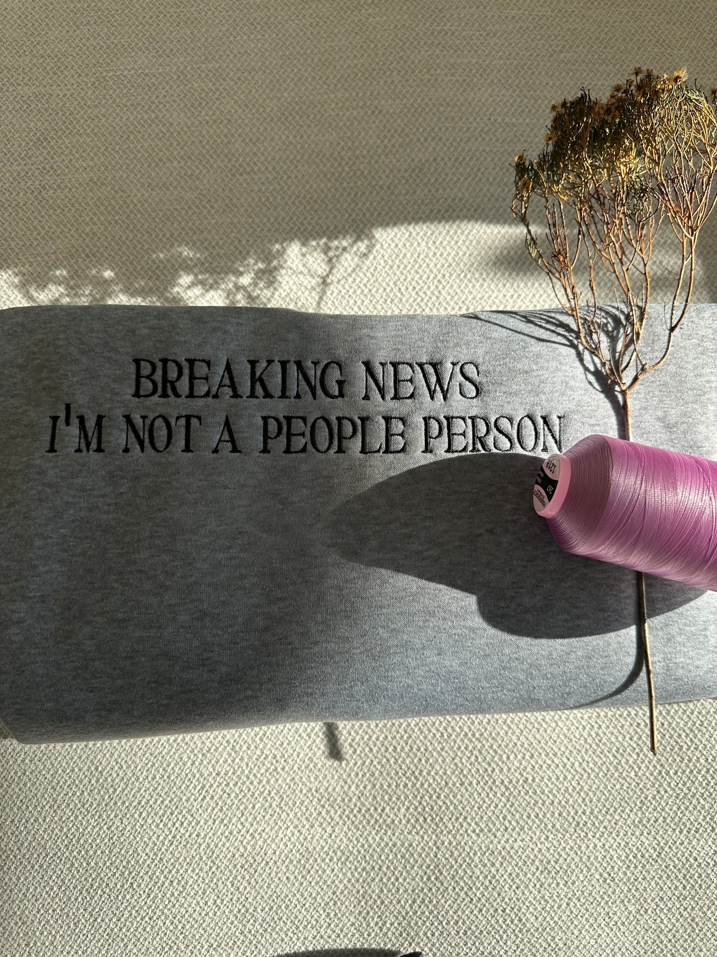 Logos embroidery, custom embroidery, Decorative stone with engraved text 'BREAKING NEWS I'M NOT A PEOPLE PERSON' on a neutral background Brisbane