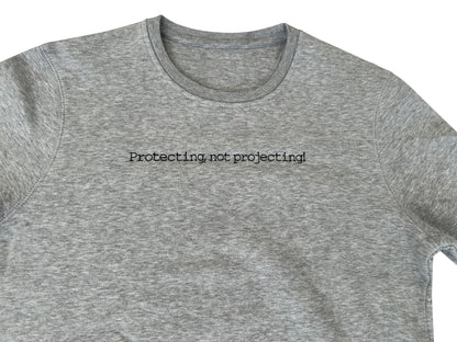 Gray t-shirt with 'Protecting not projecting' text on a white background